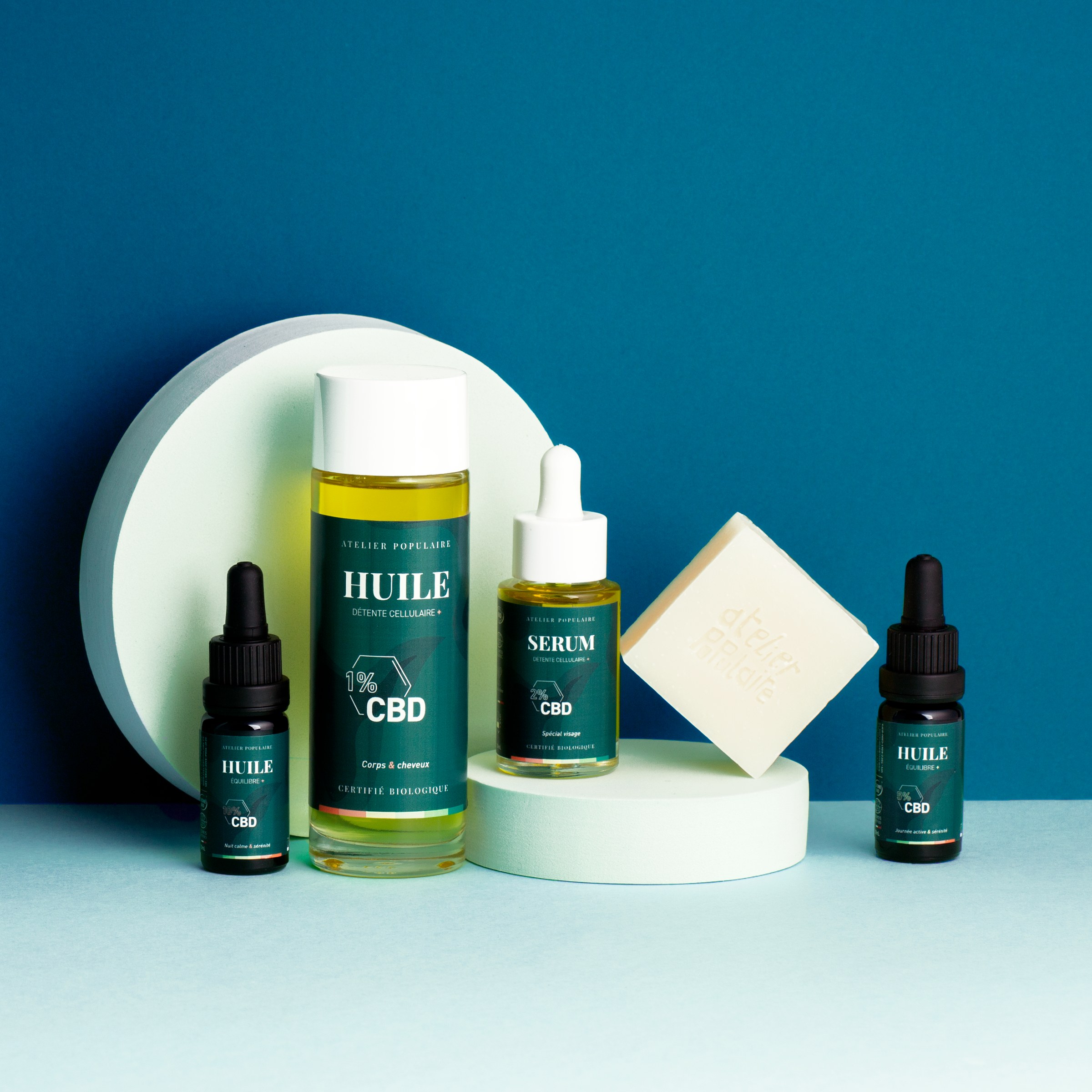 Gamme de soins CBD Atelier Populaire : huile, sérum, flacons compte-gouttes et savon.