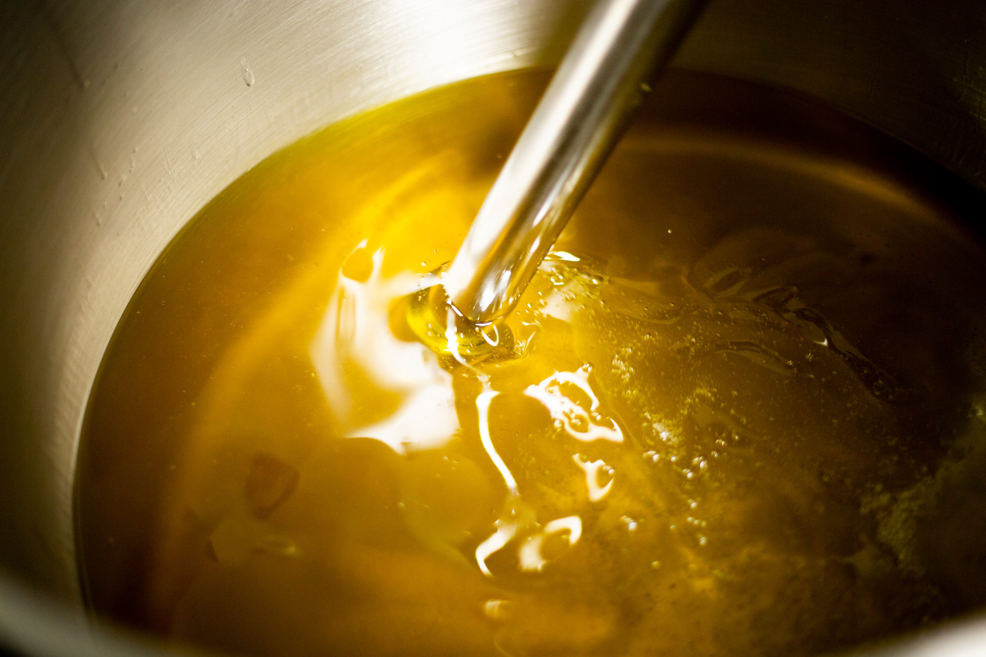 Huile d'olive dorée en train d'être mixée dans la cuve de saponification.